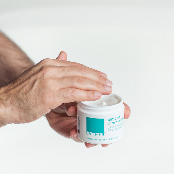 Man holding jar of shaving crème about to grab some out of the jar.