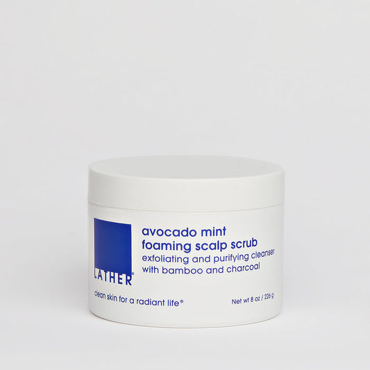 A white jar of Avocado Mint Foaming Scalp Scrub with blue label text, placed against a plain background.
