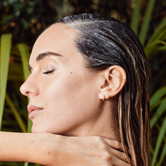 Person with eyes closed and Avocado Mint Scalp Scrub applied to their hair.
