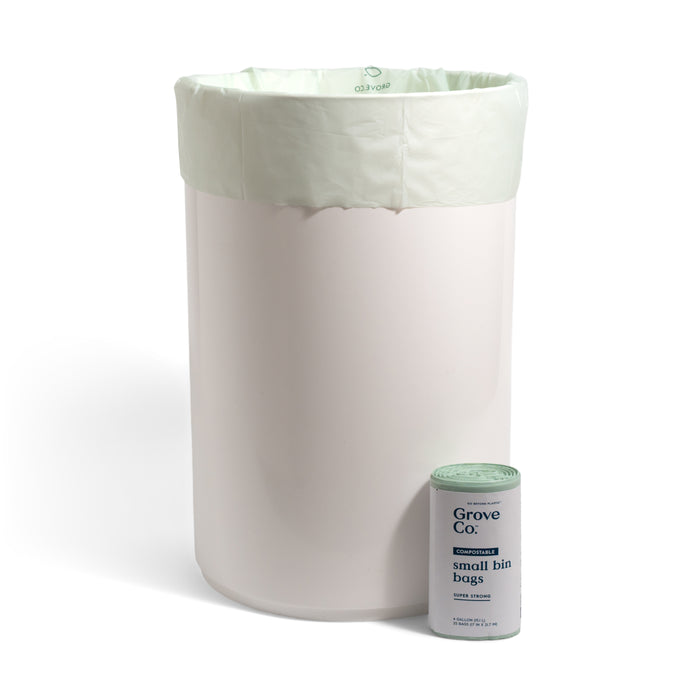 A white trash bin lined with Grove Co. Compostable Food Scrap Bags - 4 Gallon sits next to a matching container, perfect for use in kitchen compost pails or small bins.