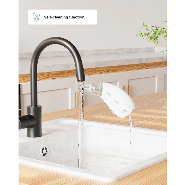 Momcozy Nasal Aspirator being rinsed under kitchen faucet over white sink, text reads "Self-cleaning function," light background.