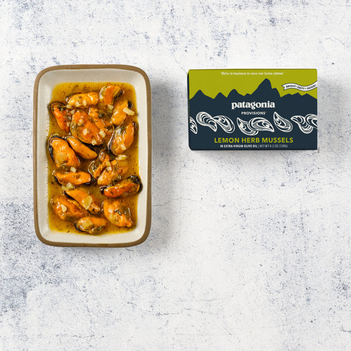 A rectangular dish of Mussels Lemon Herb by Patagonia Provisions sits next to its closed box on a light textured surface.