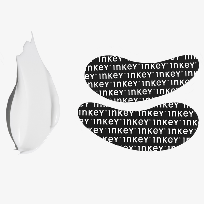 Two black reusable Inkey Eye Patches with a repeating white 'inkey' logo pattern, shown next to a white eye cream smear on a light gray background.