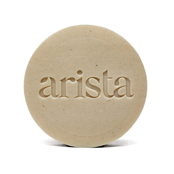 Beige round shampoo bar with arista embossed across the center.