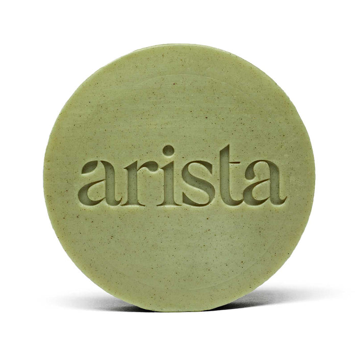 Close-up of pale green round arista shampoo bar with embossed lettering