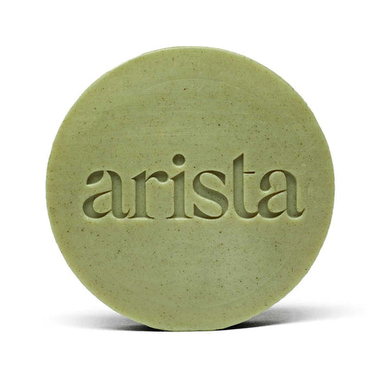 Close-up of pale green round arista shampoo bar with embossed lettering