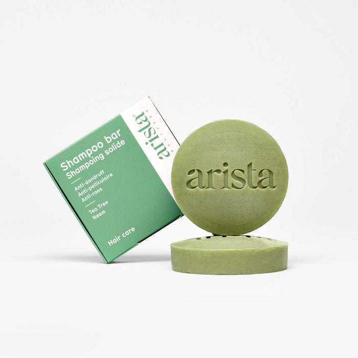 Green shampoo bar box beside a round green soap embossed with arista
