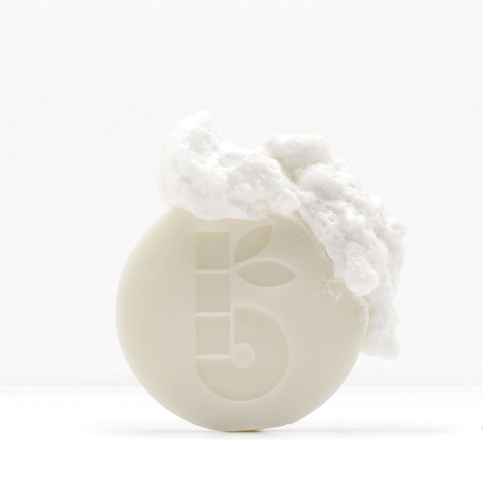 Shaving Bar product with foam on top of a white container against a clean white background