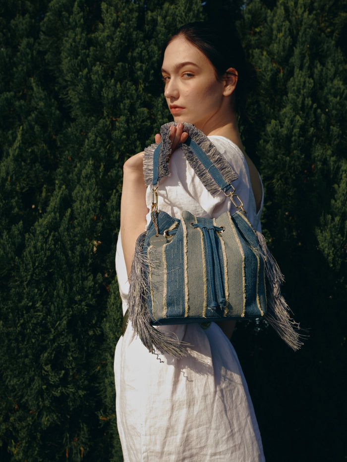 Striped denim patchwork bucket bag with fringe handle and tassel sides wholesale