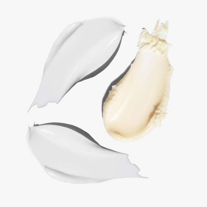 Three swatches of cream product on a clean white background: two opaque white swatches and one warm beige swatch showing the texture and finish.