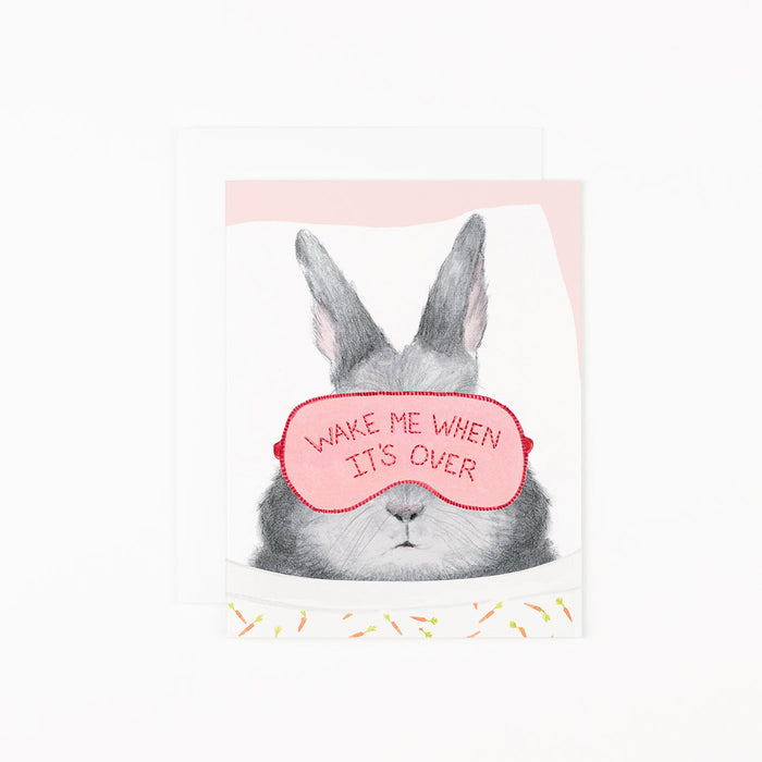Illustration on soft white paper of a hand-drawn bunny laying down, wearing a sleep mask with the phrase "Wake Me When It's Over" and carrot printed sheets, by Dear Hancock.